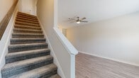 Located at 2875 Trough Springs Road in Clarksville, Tennessee, this two-story home offers 2 bedrooms and 3 bathrooms thoughtfully distributed across two well-proportioned floors. The main level features a bright, open living room with light-toned luxury vinyl plank flooring, a ceiling fan, and a window that invites natural light. The kitchen and an additional bathroom round out the first floor, which also includes a carpeted staircase with a clean white banister leading to the upper level. The second floor hosts both bedrooms, including a generously sized primary bedroom with soft carpet, a ceiling fan, a window with outdoor views, and a dedicated closet. The second bedroom is equally comfortable, featuring the same carpet flooring and ceiling fan. Two additional bathrooms serve the upper level, one featuring a granite-topped vanity with gray cabinetry and hardwood-style flooring, and another with a full tub and shower surround with built-in shelving. Neutral, warm-toned walls are consistent throughout the home, contributing to a clean and cohesive aesthetic. The home also features two closets and a hallway, providing practical storage and circulation. Overall, the space presents a well-maintained, move-in-ready layout ideal for comfortable everyday living.