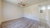 Located at 1328 E Hedrick Dr in Tucson, Arizona, this single-story home offers a clean, modern interior with consistent wood-look flooring throughout every room. The open living area is bright and airy, benefiting from natural light through large windows dressed with vertical blinds, and is finished with a ceiling fan overhead. A front entry door opens directly into this welcoming space, which flows seamlessly toward the kitchen. The kitchen is well-appointed with white shaker-style cabinetry, granite-look countertops, a double-basin stainless steel sink, and a full suite of stainless steel appliances including a refrigerator, gas range, microwave, and dishwasher. A window above the sink adds natural light to the workspace. The bedrooms are generously sized, each featuring ceiling fans and windows that bring in views of the surrounding greenery. One bedroom includes a sliding glass door providing direct outdoor access. Two bathrooms serve the home, each with a tub-shower combination with tile surround, a vanity with granite-look countertops, white cabinetry, and wood-look flooring. The overall aesthetic is clean and neutral, with light-toned walls and a cohesive modern finish throughout the entire home.