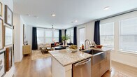 Located at 9302 Fry Rd in Cypress, TX, this well-appointed 2-bedroom, 2-bathroom residence offers a thoughtfully designed single-level layout with modern finishes throughout. Wood-look flooring flows seamlessly across the entire space, complemented by crisp white walls and recessed lighting.

The open-concept kitchen and living area serves as the heart of the home. The kitchen features a large granite-topped island with an integrated farmhouse sink and seating for multiple guests, sleek taupe cabinetry, stainless steel appliances, and a classic subway tile backsplash. The adjacent living room is bathed in natural light from expansive windows dressed with elegant dark curtains, and is equipped with a ceiling fan for year-round comfort.

A welcoming hallway adorned with gallery-style wall art leads to the two bedrooms. The primary bedroom offers generous proportions, large windows with outdoor views, a ceiling fan, and direct access to an en-suite bathroom featuring granite countertops, wood-toned cabinetry, and a tub-shower combination. A spacious walk-in closet with built-in shelving and hanging rods provides ample storage. The second bedroom mirrors the bright, airy feel with wide windows and a ceiling fan. Both bathrooms echo the same polished design aesthetic found throughout the residence.