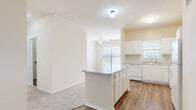This single-story, 3-bedroom, 2-bathroom home offers a practical and comfortable layout designed for everyday living. The kitchen is a standout feature, equipped with white cabinetry, granite-look countertops, white appliances including a range, microwave, dishwasher, and refrigerator, and a peninsula island that opens toward the living area. Rich hardwood-style flooring runs throughout the kitchen and dining space, while natural light streams in through multiple windows. The living area connects seamlessly to the kitchen and features a ceiling fan overhead. Each of the three bedrooms is carpeted and equipped with a ceiling fan, offering a cozy and quiet retreat. The primary bedroom includes built-in shelving and a dedicated desk nook, along with access to a closet. Windows in each bedroom provide natural light and outdoor views. The two bathrooms are finished with wood-style flooring, white vanities with ample counter space, and tiled bathtub-shower combinations. Two closets provide additional storage throughout the home. A hallway connects the bedroom wing to the main living spaces, creating a clear and efficient flow. Overall, the home presents a clean, neutral palette with warm tones that create an inviting and move-in-ready atmosphere.