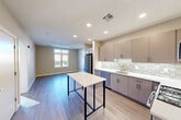 Located at 21 Charles St, Unit 303C in Cambridge, MA, this modern one-bedroom, one-bathroom residence offers a thoughtfully designed open-concept layout with contemporary finishes throughout. Light wood-style flooring flows seamlessly across the living, dining, and kitchen areas, creating a cohesive and inviting atmosphere enhanced by recessed lighting.

The kitchen is a standout feature, equipped with stainless steel appliances including a French door refrigerator, gas range, microwave, and dishwasher. Sleek gray cabinetry pairs with a mosaic tile backsplash and white quartz countertops, while a freestanding island provides additional prep and casual dining space. A gold-tone faucet adds a refined accent to the design.

The open living area benefits from a large window that invites natural light and offers views of the surrounding neighborhood. The bedroom is generously proportioned, featuring an expansive floor-to-ceiling window that fills the room with sunlight and frames outdoor views.

The bathroom is finished with clean white vertical subway tile in the tub-shower surround, complemented by brushed gold fixtures and hardware. A white vanity with an undermount sink completes the polished look. Additional conveniences include two closets, in-unit laundry, a hallway, and a dedicated entrance, making this a well-appointed and functional urban residence.