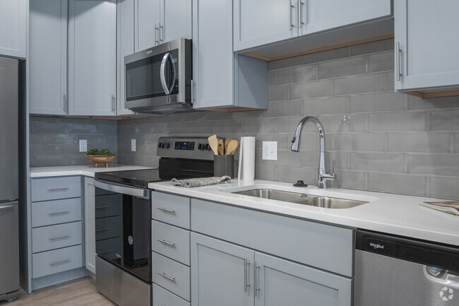 Kitchens feature quartz countertops, stainless steel appliances, and glass subway tile backsplashes - Tree Farm Lofts