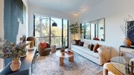 Located at 1 Riva Row in Spring, TX, this thoughtfully designed one-bedroom, one-bathroom residence offers a sleek, modern aesthetic throughout its efficiently organized single floor. The open-concept living, dining, and kitchen area serves as the heart of the home, anchored by a stunning kitchen outfitted with light wood cabinetry, a quartz waterfall-edge island with bar seating, stainless steel Bosch appliances, a gas range, and a built-in dishwasher. Matte black pendant lights add a striking contrast to the bright, airy palette. The living area is bathed in natural light from expansive floor-to-ceiling windows and a glass-panel balcony door that frames serene, wooded views of the surrounding tree canopy. The bedroom continues the nature-forward theme with its own large window overlooking the greenery, complemented by light hardwood flooring found throughout. A well-appointed bathroom features a glass-enclosed walk-in shower, light wood vanity, and large-format tile flooring. Two closets, including a spacious walk-in, provide generous storage. A dedicated laundry area and pantry further enhance the functional layout of this refined, contemporary residence.