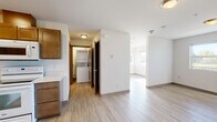 This single-floor unit at 175 Pump Dr in Burlington, Washington offers a thoughtfully designed layout that balances comfort and functionality. Light-toned vinyl plank flooring runs consistently throughout the space, lending a clean, cohesive look to every room.

The kitchen is a standout feature, outfitted with rich warm-toned cabinetry extending to the upper walls for generous storage, light countertops, a double-basin sink, and a full suite of white appliances including a refrigerator, electric range, built-in microwave, and dishwasher. Recessed lighting illuminates the workspace effectively.

The open living area is bright and airy, benefiting from multiple windows that invite natural light and offer views of the surrounding outdoor greenery. A private balcony door provides direct access to the outdoors. The space is versatile and well-suited for a variety of furniture arrangements.

A dedicated laundry closet houses a stacked washer and dryer unit, offering the convenience of in-unit laundry. The bathroom features warm wood-toned cabinetry with a vanity sink and is finished consistently with the rest of the unit's neutral palette.

Throughout, the unit maintains a clean, move-in-ready aesthetic with white walls, modern fixtures, and a practical flow between spaces, making it a functional and comfortable residence in Burlington, WA.
