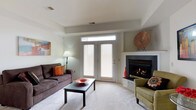 Located at 105 Amberley Drive in Blue Bell, Pennsylvania, this single-floor residence offers a thoughtfully designed living space that balances comfort and functionality. The living room serves as the heart of the home, highlighted by a classic fireplace with a clean white mantel and dark surround, creating a warm and inviting focal point. French doors with transom windows above allow natural light to flow into the room while providing access to the outdoors. The neutral color palette — soft whites and warm grays — lends the space an airy, open feel. Carpeted flooring adds a layer of coziness underfoot, complementing the relaxed atmosphere. The tray ceiling adds subtle architectural interest and a sense of depth to the room. Overall, the space presents a clean, well-maintained interior that is both practical and comfortable, ideal for everyday living in the established Blue Bell community of Montgomery County, Pennsylvania.