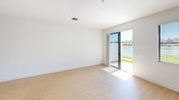 This contemporary townhouse in Miramar, Florida offers 1310 square feet of living space across two floors. The ground floor spans 580 square feet, while the upper level provides 740 square feet. The home features three bedrooms, including a spacious 170 square foot primary bedroom, and three full bathrooms.

The open-concept main living area combines the kitchen and living room, creating a seamless flow for entertaining. The kitchen boasts modern white cabinetry, stainless steel appliances, and granite countertops with a breakfast bar. Pendant lighting and track lighting add a stylish touch to the space.

Large windows and sliding glass doors allow ample natural light to flood the interiors, while also offering views of the surrounding landscape. The bedrooms feature light wood-look flooring and windows with horizontal blinds for privacy.

The bathrooms are appointed with contemporary fixtures, including glass-enclosed showers and granite vanity tops. The property also includes a single-car garage with a standard roll-up door and concrete flooring.

Throughout the home, neutral white walls and light flooring create a bright, airy ambiance. The property's layout includes two hallways for easy navigation between rooms, and a staircase connecting the two floors. A closet provides additional storage space, completing this well-designed townhouse.