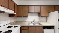 Located at 6851 Sharon Ct in Columbus, Ohio, this single-floor residence offers a practical and comfortable layout designed for everyday living. The kitchen is a standout feature, showcasing warm-toned wood cabinetry that extends to the upper walls, providing generous storage space for all culinary needs. A double-basin stainless steel sink anchors the countertop, which features a speckled composite surface that balances durability with clean aesthetics. The kitchen is equipped with a white electric range and a black dishwasher, offering a functional contrast against the cabinetry. The neutral white walls throughout create a bright, open atmosphere that allows the rich wood tones of the cabinets to take center stage. The single-floor layout ensures easy accessibility and a seamless flow throughout the home. The overall design of the space reflects a straightforward, functional approach to residential living, with classic finishes and well-organized storage that cater to practical daily needs. This Columbus property presents a solid opportunity for those seeking a well-maintained, move-in-ready home in a residential neighborhood.