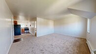 Located at 228 NY-376 in Hopewell Junction, NY, this one-bedroom, one-bathroom unit offers a practical and well-organized single-floor layout. The spacious living room features neutral wall-to-wall carpeting and an open sightline toward the kitchen, creating a cohesive and airy feel throughout the main living area. Multiple windows allow natural light to filter into the space, contributing to a bright and welcoming atmosphere.

The kitchen is equipped with warm wood-toned cabinetry, a stainless steel gas range, a refrigerator, and a mosaic tile backsplash that adds a touch of character. Hardwood-style flooring in the kitchen contrasts nicely with the carpeted living areas.

The bedroom is generously sized, featuring plush carpeting, a closet, and a window with views of the surrounding greenery. Baseboard heating is present throughout, ensuring year-round comfort. Three closets total provide ample storage across the unit.

The bathroom is finished with warm earth-toned ceramic tile surrounding a full soaking tub with a shower, complemented by a white vanity and tile flooring. A small window brings in natural light and ventilation. Overall, this unit offers a clean, functional living environment in a convenient Dutchess County location.