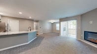Located at 1630 Crossings Parkway in Westlake, Ohio, this 2-bedroom, 2-bathroom residence offers a thoughtfully designed single-floor layout that balances comfort and modern style. The open-concept living and kitchen area forms the heart of the home, where plush carpeting extends throughout the spacious living room, which is anchored by a sleek fireplace and a sliding glass door that floods the space with natural light and provides direct outdoor access. The kitchen is a standout feature, showcasing white shaker cabinetry, stone-look countertops with striking veining, a curved peninsula with an integrated sink and matte black faucet, and a full suite of stainless steel appliances, all set atop wood-look flooring. Both bedrooms are generously proportioned, finished with soft carpeting and bright windows that invite natural light. The primary bedroom offers a comfortable and private retreat. The bathrooms are cleanly finished, with one featuring wood-look tile flooring, white cabinetry with matte black hardware, a tub-shower combination with subway tile surround, and a well-lit vanity mirror. Neutral gray tones carry throughout the home, creating a cohesive and contemporary ambiance.