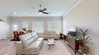 This single-story home in Rosharon, Texas offers a well-designed layout across three bedrooms and two and a half bathrooms. The living room is bright and inviting, featuring crown molding, wood-look flooring, a ceiling fan, and multiple windows fitted with blinds that allow abundant natural light to fill the space. The open arrangement flows naturally into the dining area, which benefits from its own set of large windows and direct access to an exterior door.

The kitchen is thoughtfully appointed with white cabinetry, granite-look countertops, a subway tile backsplash, and stainless steel appliances, including a range, microwave, and refrigerator. Light wood flooring continues throughout these shared spaces, contributing to a cohesive, modern aesthetic.

The bedrooms are carpeted and generously sized, each with ceiling fans and ample natural light. Vaulted ceilings elevate the primary bedroom, which connects to a walk-in closet and an en-suite bath. A full secondary bathroom features a dual-sink vanity with granite countertops, a tiled tub-shower combination, and tile flooring. The attached two-car garage provides substantial storage and utility space, completing this practical and well-finished home.