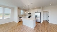 Located at 2405 Herrons Nest Pl NW in Concord, NC, this well-appointed single-floor home offers three bedrooms, two full bathrooms, and a thoughtfully designed open layout. The kitchen is a standout feature, showcasing white shaker cabinetry extending to the ceiling, a large center island with quartz countertops, stainless steel appliances including a refrigerator, range, microwave, and dishwasher, and pendant lighting that adds a modern touch. The kitchen flows seamlessly into the living area, which is bathed in natural light from multiple windows with views of the surrounding neighborhood. Warm, light wood-style flooring runs consistently throughout the entire home, creating a cohesive and inviting atmosphere. The generously sized primary bedroom includes a walk-in closet outfitted with wire shelving systems, providing ample storage. The two full bathrooms are finished in a clean, contemporary style, each featuring white subway tile tub-shower combinations, white vanities with quartz countertops, and matte black hardware and fixtures that provide a striking contrast. Additional bedrooms offer bright, windowed spaces with views and recessed lighting. The home's neutral palette, modern finishes, and well-organized floor plan make it a functional and stylish residence.