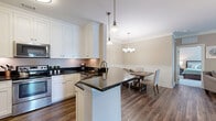 This single-floor, 2-bedroom, 3-bathroom residence offers a refined and functional layout with classic design details throughout. The open-concept kitchen and dining area serve as the heart of the home, featuring white shaker cabinetry, dark granite countertops, stainless steel appliances, and a central island with additional counter space. Pendant lighting and a chandelier above the dining area lend an elegant touch, while rich hardwood-style flooring ties the space together seamlessly.

The living room is bright and welcoming, with multiple windows allowing ample natural light and crown molding adding a polished architectural detail. Ceiling fans are present in both bedrooms, contributing to year-round comfort. The generously sized primary bedroom includes plush carpeting and direct access to an en-suite bathroom, which is outfitted with a wide granite-topped vanity, white cabinetry, and a glass-enclosed shower. The second bedroom is equally comfortable, with its own nearby bathroom featuring a shower-tub combination.

Three closets provide abundant storage throughout the home, complemented by a dedicated laundry room with a full-size washer and dryer. The neutral, warm color palette and consistent use of quality materials create a cohesive and inviting ambiance throughout the entire residence.