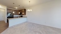 Located at 34011 Harvard Ave in Millsboro, Delaware, this single-floor residence offers a thoughtfully designed layout that balances comfort and practicality. The kitchen is a standout feature, showcasing rich dark cabinetry with ample storage, granite-style countertops, and a full suite of black appliances including a side-by-side refrigerator, electric range, and built-in microwave. Wood-look flooring grounds the kitchen and flows into the adjacent dining area, which is highlighted by an elegant chandelier and a peninsula counter that connects seamlessly to the living space, all finished with plush neutral carpeting. The bedrooms are generously proportioned, each featuring ceiling fans, soft carpeting, and windows with blinds that invite natural light while maintaining privacy. Two bathrooms serve the residence: one features a tub-shower combination, a dark-toned vanity, and wood-look flooring, while the other offers a walk-in glass-enclosed shower, a matching vanity, and the same warm flooring. A dedicated laundry area houses a full-size GE top-loading washer and dryer alongside wire shelving for added storage. Throughout the home, a neutral color palette and clean finishes create a bright, cohesive ambiance well-suited to a variety of lifestyles.