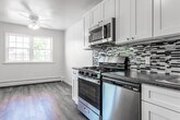Located at 644 Silver Lake Scotchtown Rd in Middletown, NY, this single-floor residence offers a practical and comfortable layout with clean, neutral finishes throughout. The kitchen is a standout feature, equipped with stainless steel appliances including a gas range, microwave, and refrigerator. White shaker-style cabinetry, dark granite-style countertops, a mosaic tile backsplash, and wood-look vinyl flooring combine to create a functional and stylish cooking space. The living areas are generously proportioned, finished with soft wall-to-wall carpeting and neutral-toned walls that lend a calm, versatile ambiance. Windows allow natural light to filter in, offering pleasant views of the surrounding greenery. A closet and a wall-unit air conditioner are also present in the main living area. The bedrooms are well-sized, featuring plush carpeting, ample wall space, and easy access to adjacent rooms. Baseboard heating runs along the perimeter of multiple rooms, ensuring year-round comfort. The bathroom is bright and clean, featuring full white tile surrounding a soaking tub with an overhead shower, chrome fixtures, and a window that invites natural light. The overall layout, as seen in the dollhouse view, is compact and efficiently organized, making excellent use of the available single-floor footprint.