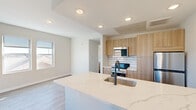 This thoughtfully designed 1-bedroom, 1-bathroom unit combines modern aesthetics with functional living across a single floor. The open-concept kitchen serves as the centerpiece, showcasing a striking quartz island countertop with elegant gold veining, an undermount sink with a matte black gooseneck faucet, and light wood cabinetry that extends floor to ceiling. A white subway tile backsplash complements the stainless steel appliances, including a built-in microwave, electric range, and refrigerator. Recessed lighting and light hardwood-style flooring run throughout, creating a bright and cohesive atmosphere.

The living area flows naturally from the kitchen, receiving natural light through a window that adds to the airy, open feel of the space. The bedroom offers a comfortable footprint with a full-width closet featuring clean white bi-fold doors and the same warm flooring found throughout the unit.

The bathroom is appointed with a walk-in shower finished in floor-to-ceiling white vertical tile with contrasting dark grout, complemented by a dark mosaic tile floor and a built-in niche for storage. A hallway connects the main living areas to the private spaces, ensuring a logical and efficient layout. Overall, the unit presents a clean, contemporary design with quality finishes throughout.