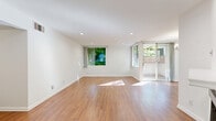 Located on Burbank Boulevard in the Woodland Hills neighborhood of Los Angeles, this single-floor residence offers three bedrooms, two bathrooms, and a well-organized layout across a comfortable footprint. The open living and dining area is a standout, featuring warm wood-look flooring, crisp white walls, recessed lighting, and a classic fireplace. Large windows and a sliding glass door flood the space with natural light and provide direct access to a private balcony overlooking lush greenery. The galley-style kitchen is well-appointed with white shaker cabinetry, marble-look countertops, stainless steel hardware, a double-basin sink, and built-in appliances — all complemented by matching wood-look flooring and recessed lighting. The primary bedroom is generously sized, featuring hardwood-style floors, a large picture window with garden views, and recessed lighting. The additional bedrooms are finished with plush carpeting, mirrored sliding closet doors, and windows that bring in natural light and outdoor views. Three closets throughout provide ample storage. The bathrooms include a tub-shower combination with glass enclosure. A hallway connects the rooms efficiently, and dual entrances add everyday convenience.