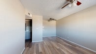 This single-floor unit offers a well-organized layout with a consistent, neutral design aesthetic throughout. Wood-look plank flooring runs across all living spaces, complemented by crisp white baseboards and soft gray walls that create a clean, cohesive ambiance. Textured popcorn ceilings and ceiling fans equipped with integrated lighting fixtures are present in every room, providing both comfort and functionality.

The kitchen is a standout feature, showcasing dark gray cabinetry, a stainless steel double-basin sink, and a stainless steel electric range with an overhead ventilation hood. A linear mosaic tile backsplash adds a modern, stylish touch to the space.

The living and dining areas are open and well-proportioned, offering a welcoming environment with natural light filtering in through blinds-covered windows. The entry area includes a front door with a window, allowing additional light into the space.

The bedrooms are generously sized, each featuring the same wood-look flooring and ceiling fans. At least one bedroom includes a closet with a rod and shelving, providing practical storage. Additional doors suggest access to further storage or utility spaces.

Overall, the unit presents a clean, move-in-ready environment with updated finishes, practical storage solutions, and a functional floor plan suited for everyday living.