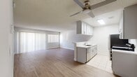 Located at 6000 Buckingham Parkway in Culver City, California, this single-story one-bedroom residence offers a well-organized and efficiently designed layout. Light wood-tone flooring flows throughout the main living areas, complemented by crisp white walls and textured ceilings, creating a clean and airy atmosphere.

The open-concept living room is generously sized, bathed in natural light streaming through large vertical-blind-covered windows and a sliding glass door that opens to the exterior. A ceiling fan adds comfort to the space. The kitchen is neatly appointed with white cabinetry, white countertops, stainless steel appliances including a refrigerator and electric range, and a built-in dishwasher. A skylight overhead brightens the kitchen with natural light, while tile flooring provides a practical and polished finish.

The spacious primary bedroom is one of the standout features of this residence, offering ample room and a window for natural light. It includes mirrored sliding closet doors that open to a well-shelved storage area, enhancing both functionality and the sense of space. A hallway connects the main living areas to the bedroom and bathroom, providing a logical and private flow throughout the unit. Overall, the space presents a bright, neutral, and move-in-ready environment in a prime Culver City location.