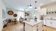 Located at 2670 Meadow Creek Rd in Kissimmee, FL, this two-story residence combines modern design with warm, inviting finishes. The open-concept main level seamlessly connects the kitchen, dining, and living areas. The kitchen is a standout, outfitted with crisp white shaker cabinets, granite countertops, a central island with seating, stainless steel appliances, a subway tile backsplash, and pendant lighting overhead. Light wood-style flooring flows throughout the main level, enhancing the bright, airy atmosphere. The dining area accommodates a generous table and is positioned conveniently near the staircase. The living room features a ceiling fan, large windows with sheer curtains, and a relaxed, neutral aesthetic accented by woven wall décor. Upstairs, the primary bedroom offers plush carpeting, multiple windows for natural light, and a ceiling fan. Additional bedrooms include a cozy room with bunk beds and carpeted flooring, ideal for multiple occupants. Bathrooms are well-appointed with granite-topped vanities, white cabinetry with black hardware, and clean tile work, including a full bath with a tub-shower combination. Throughout both floors, the design maintains a cohesive, contemporary palette of whites and neutrals.
