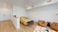 Located at 1925 W North Temple in Salt Lake City, Utah, this one-bedroom, one-bathroom unit offers a smartly designed open-concept floor plan that maximizes every inch of its compact footprint. Light wood-look flooring flows consistently throughout the space, enhancing the bright, cohesive aesthetic.

The combined living, dining, and kitchen area forms the heart of the unit. The kitchen is outfitted with crisp white shaker cabinets extending to the ceiling, a white subway tile backsplash, dark countertops, and a full suite of stainless steel appliances including a refrigerator, range, microwave, and dishwasher. A peninsula counter with a raised bar provides a natural division between the kitchen and dining area, where a window brings in generous natural light.

The bedroom is a defined, private space partially separated by a half-wall partition, maintaining an open feel while offering functional separation. Recessed lighting illuminates the room cleanly. The bathroom features a full tub-shower combo with white tile surround, a vanity with dark hardware, and wood-look flooring. Additional conveniences include in-unit laundry and two closets for ample storage. A hallway connects the rooms efficiently, completing this well-appointed, move-in-ready unit.