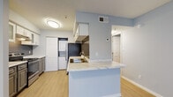 Located at 4610 N Armenia Ave in Tampa, FL, this single-floor unit offers a well-designed layout with a cohesive, modern aesthetic throughout. The living area is finished with light wood-style flooring and features multiple windows with blinds and vertical shades, allowing natural light to fill the space while maintaining privacy. A front entry door opens directly into this bright, open area.

The kitchen is a standout feature, anchored by a peninsula with a striking marble-look countertop and an undermount sink. White upper cabinetry contrasts with gray lower cabinets, while a dark subway tile backsplash adds texture and depth. Stainless steel appliances, including a gas range and refrigerator, complete the functional cooking space. A stacked washer and dryer unit is conveniently integrated within the kitchen area, adding in-unit laundry accessibility.

The bedroom is carpeted for comfort and features a ceiling fan with a window that brings in natural light and views of the surrounding greenery. The soft blue-gray wall color carries consistently throughout the unit, creating a calm and cohesive ambiance. The textured ceilings and clean white trim add to the unit's polished, move-in-ready presentation. Overall, this space combines practical features with tasteful finishes in a convenient Tampa location.