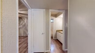 This single-floor space is thoughtfully laid out to maximize functionality and comfort. The interior is unified by wood-look plank flooring that extends throughout all areas, providing a clean and cohesive aesthetic.

The kitchen is equipped with white cabinetry, a stainless steel sink, warm granite-style countertops, and a tile mosaic backsplash that adds a decorative touch. A window above the entry door allows natural light to filter in, and space for a full-size refrigerator is included.

The living area is open and well-proportioned, featuring neutral-toned textured walls, a textured ceiling, and a large window that invites ample natural light. The space offers a versatile layout suitable for a variety of furniture arrangements.

The bedroom is a comfortable, private retreat equipped with a ceiling fan and light fixture. Textured walls in a warm neutral tone contribute to the room's calm atmosphere.

The bathroom features a split-style layout, with white vanity cabinetry and a granite-style countertop on one side, and a dedicated bathtub and shower area separated by a door for added privacy. A small window in the tub area provides ventilation and natural light.

A closet with a standard door provides convenient storage. Throughout the space, white trim and door frames create a fresh, clean contrast against the warm wall tones.