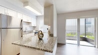 Located at 1201 Seminole Blvd in Largo, Florida, this single-floor residence offers a clean, contemporary design throughout. The open-concept living and dining area is finished with light wood-style flooring and crisp white walls, creating a bright and airy atmosphere. Natural light flows freely through a sliding glass door that opens to a private balcony, offering pleasant outdoor views of the surrounding greenery.

The kitchen is thoughtfully designed with white cabinetry, granite countertops, and a suite of stainless steel appliances, including a refrigerator, dishwasher, and range. A peninsula counter with seating space connects the kitchen to the main living area, making it ideal for both everyday use and casual entertaining. A window above the sink brings in additional natural light.

The bedroom features plush carpeting and neutral tones, providing a comfortable and restful retreat. A textured ceiling is present throughout the unit, adding a classic touch to the overall aesthetic. The bathroom is well-appointed with a granite-topped vanity, white cabinetry with brushed hardware, wood-style flooring, and a full tub-shower combination. The unit's layout is efficient and well-organized, with adequate closet and storage space integrated throughout the floor plan.
