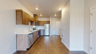 Located in the desirable NW 24th neighborhood of Portland, Oregon, this modern single-floor unit offers a thoughtfully designed open-concept layout with clean lines and contemporary finishes throughout. Wide-plank wood-look flooring flows seamlessly across the living and kitchen areas, creating a warm and cohesive aesthetic.

The kitchen is a functional centerpiece, outfitted with warm wood-toned cabinetry, light countertops, and a full suite of stainless steel appliances including a refrigerator, electric range, built-in microwave, and dishwasher. A single-basin sink sits beneath recessed lighting, completing a well-appointed culinary space that opens directly into the spacious living area.

The bedroom benefits from large windows that invite natural light and offer views of the surrounding Portland neighborhood, contributing to a bright and airy feel. A generously sized walk-in closet with wire shelving provides ample storage.

The bathroom mirrors the unit's modern design language with matching wood-toned cabinetry, a white countertop vanity, and durable flooring. A dedicated laundry closet houses a full-sized top-load washer and dryer, adding everyday convenience. Recessed lighting throughout and crisp white walls enhance the unit's clean, contemporary ambiance.