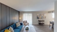 This single-floor home in Indianapolis offers a well-designed layout with thoughtful modern updates throughout. The living room is a standout space, anchored by a bold dark vertical shiplap accent wall that adds depth and character. Wood-look flooring flows underfoot, while a large sliding glass door with vertical blinds fills the room with natural light and provides outdoor access. The kitchen is efficiently appointed with rich dark cabinetry, white countertops, a mosaic tile backsplash, and a full suite of stainless steel appliances including a range, microwave, and refrigerator. A stacked washer and dryer unit is conveniently integrated within the kitchen area. The home includes multiple bedrooms, each featuring neutral toned walls, wood-look flooring, and windows that bring in natural light. The primary bathroom is finished with a dark vanity, marble-style countertop, framed mirror, and wall-mounted lighting. A second bathroom offers a glass-door shower and clean, simple finishes. The overall design palette of soft grays, warm whites, and dark accents gives the home a cohesive and contemporary feel throughout.