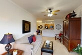 Located at 2118 W Old Spanish Trail in New Iberia, Louisiana, this well-appointed 2-bedroom, 2-bathroom single-story home offers a comfortable and functional layout. The living room serves as the heart of the home, featuring crown molding, plush carpeting, a ceiling fan with light fixture, and a bay window that draws in natural light. The space flows seamlessly into the combined dining room and kitchen, which is anchored by a pass-through counter. The kitchen is equipped with black appliances including a refrigerator, range, and microwave, complemented by warm oak cabinetry and tile flooring. The primary bedroom is generously sized, featuring a ceiling fan, multiple windows with blinds, and direct access to a walk-in closet with wire shelving. The second bedroom mirrors this comfortable feel with a ceiling fan and ample natural light. Both bathrooms include tub-shower combinations, oak cabinetry, and tile flooring. Two dedicated closets provide excellent storage throughout the home. A dedicated laundry area adds everyday convenience. The overall ambiance is warm and inviting, with consistent finishes and thoughtful details throughout.