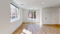 Located at 207 W Eighth St in Wilmington, Delaware, this two-story home offers a thoughtfully designed layout spread across two well-proportioned floors. The main level features an open-concept kitchen and living area bathed in natural light from large street-facing windows. The kitchen is outfitted with sleek grey cabinetry reaching to the ceiling, stainless steel appliances, a white quartz island with an undermount sink, and a pendant light fixture — combining style with practicality. The living area extends naturally from the kitchen, with light hardwood flooring and a clean, minimalist aesthetic throughout. A staircase with a warm wood handrail connects to the upper level. Three full bathrooms serve the home, each finished with large-format tile flooring, light wood vanity cabinetry, white quartz countertops, and ample natural light. The spacious primary bedroom on the upper floor includes a built-in closet with shelving and benefits from multiple windows framing views of Wilmington's historic streetscape. The second bedroom is equally bright, with large windows and hardwood floors. Throughout the home, white walls, black hardware accents, and consistent wood-tone flooring create a cohesive, modern urban aesthetic.