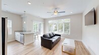 This 530 square foot apartment, located at 305 W Washington St in Champaign, IL, offers a well-designed living space that maximizes functionality. The single-floor layout comprises one bedroom, one bathroom, and an open-concept kitchen and living area. The primary bedroom, measuring 140 square feet, provides a cozy retreat with carpeted flooring and a large window offering exterior views.

The living area showcases warm wood flooring that extends throughout the main space, creating a seamless flow. A wall-mounted flat-screen TV and contemporary furniture enhance the modern aesthetic. Large windows flood the room with natural light, while offering views of the surrounding neighborhood.

The kitchen, though compact, is efficiently designed with white cabinetry, stainless steel appliances, and granite countertops. A window above the sink allows for natural light and ventilation. The bathroom features a clean, white color scheme with a granite-topped vanity and wood-look tile flooring.

Throughout the apartment, neutral wall colors and an abundance of natural light create a bright, airy atmosphere. The thoughtful design and modern finishes make this compact space feel larger and more open, ideal for comfortable urban living.
