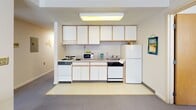 Located at 151 Dryden Rd in Ithaca, NY, this single-floor student housing unit offers a practical and comfortable layout well-suited for Cornell University students. The unit features multiple bedrooms, each furnished with a bed, a built-in desk, shelving unit, and carpeted flooring. Corner windows with horizontal blinds allow natural light to fill the sleeping areas while offering views of the surrounding campus neighborhood.

The shared living room provides a welcoming communal space with plush armchairs and a sofa arranged around a central coffee table. Corner windows continue the theme of natural light throughout, and the room offers ample space for relaxation and socializing.

The kitchen is efficiently designed with white cabinetry, a full-size refrigerator, electric stove, dishwasher, microwave, and a sink — providing everything needed for everyday cooking and meal preparation. The bathroom is clean and functional, featuring a combined shower and bathtub with sliding glass doors, a single vanity with a sink, toilet, and a well-lit mirror above.

Throughout the unit, neutral walls, carpeted living areas, and consistent light wood furnishings create a cohesive and understated aesthetic. The overall layout is thoughtfully organized to support both private study and shared living, making it an ideal residence for students at Cornell University.