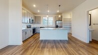 Located at 500 Lama Dr in Summerville, South Carolina, this multi-story home spans three floors and showcases a clean, modern design throughout. The kitchen is a standout feature, equipped with gray shaker-style cabinetry accented by matte black hardware, granite countertops, a white subway tile backsplash, and a full suite of stainless steel appliances. A central island with pendant lighting provides additional workspace and storage, while warm hardwood-style flooring ties the kitchen seamlessly into the open living area, which is brightened by a ceiling fan and recessed lighting. Built-in shelving near the kitchen adds practical storage and visual interest. The bedrooms are carpeted for comfort and feature ceiling fans and large windows that invite natural light and outdoor views. Generous closet spaces, including walk-in options, offer ample storage. The bathrooms are finished with the same granite vanity tops and gray cabinetry found throughout the home, complemented by wood-look flooring, white tiled tub-shower combos, a glass-enclosed shower, and matte black fixtures and hardware. The cohesive design palette of neutral whites, warm wood tones, and matte black accents creates a contemporary and inviting atmosphere across all three levels.