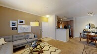 Located at 100 Hawthorne Way in Lawrence, MA, this single-floor residence offers a thoughtfully designed layout that balances comfort and functionality. The open-concept living area features warm neutral tones, crown molding, and plush carpeting, with a distinctive built-in media niche finished in bold black paint that serves as a striking focal point. A sliding glass door allows natural light to fill the space and provides outdoor access. The living area flows seamlessly into a dedicated dining space, complete with crown molding and room for a full dining set. The kitchen is well-equipped with rich wood cabinetry, dark granite-style countertops, black appliances including a gas range, microwave, and refrigerator, and durable wood-look flooring. Two carpeted bedrooms each feature accent walls in deep, moody hues and large windows that invite natural light. The full bathroom offers a rich wood vanity with a white countertop, wood-look tile flooring, and a shower-tub combination. A dedicated in-unit laundry room houses a full-size washer and dryer with overhead shelving for added storage. The residence presents a cohesive, contemporary aesthetic throughout.