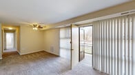 This thoughtfully designed 1-bedroom, 1-bathroom single-floor residence offers a functional and comfortable layout. The kitchen stands out with modern light wood cabinetry, granite-look countertops, stainless steel sink, and black Whirlpool appliances including an electric range and refrigerator, all illuminated by overhead flush lighting and easy-care tile flooring. The combined dining and living room is a bright, open space anchored by wall-to-wall carpeting and a large sliding glass door flanked by full-length vertical blinds, inviting abundant natural light and outdoor access. The bedroom is a comfortable retreat featuring soft carpet, a ceiling fan with light fixture, a natural light-admitting window with blinds, and an exceptionally wide built-in closet with full-panel bifold doors offering generous storage capacity. Additional closets throughout the unit provide further storage flexibility. The bathroom is clean and classic, finished with white subway tile wainscoting, a combined tub and shower, a white vanity with mirror, and warm vanity lighting. Overall, the unit presents a neutral, move-in-ready palette with practical finishes and a bright, airy ambiance throughout.