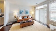 This thoughtfully designed 1-bedroom, 1-bathroom residence offers a modern, open-concept layout that seamlessly connects the kitchen, dining, and living areas. The kitchen is equipped with a full suite of stainless steel appliances, including a gas range, microwave, dishwasher, and refrigerator, all complemented by light wood cabinetry, crisp white quartz countertops, and a peninsula with bar seating — ideal for casual dining or entertaining. Dark hardwood-style flooring runs throughout the main living areas, adding warmth and contrast to the neutral color palette.

The living room is bright and inviting, featuring large sliding glass doors that welcome generous natural light and provide views to the outside. The private bedroom is carpeted for comfort, fitted with a ceiling fan, and features windows dressed with blinds and sheer curtains that create a calm, restful atmosphere. A full bathroom serves the residence with a wood-toned vanity, white quartz countertop, a soaking tub and shower combination, and light tile flooring. Clean lines, recessed lighting, and a cohesive contemporary aesthetic are carried consistently throughout the home, making it a polished and functional living space.