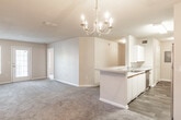 Located at 100 Crossing Pl in Commerce, GA, this single-floor, 2-bedroom, 2-bathroom residence offers a practical and comfortable layout designed for everyday living. The open living and dining area is generously sized, featuring plush carpeting, neutral-toned walls, and an elegant chandelier that adds a refined touch to the space. Natural light filters in through multiple windows fitted with blinds, creating a bright and welcoming atmosphere throughout.

The kitchen features white cabinetry with wood-tone accents, a black range, and a breakfast bar that seamlessly connects to the main living area. Adjacent to the kitchen is a utility area with a dedicated laundry space and electrical panel access, finished with durable wood-look flooring that extends through the kitchen and bathrooms.

Both bedrooms are well-proportioned with soft carpeting and ample natural light provided by large windows. The primary bedroom includes a walk-in closet for added storage convenience. Each bathroom is thoughtfully equipped with accessibility features, including grab bars near the toilet and tub/shower areas. One bathroom includes a vanity with a large mirror and under-sink cabinetry, while the other offers a tub-shower combination with white tile surround. The textured ceilings throughout add a classic finishing detail to this functional and inviting home.