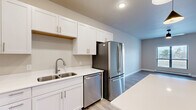 Located at 421 S Green Ave in New Richmond, WI, this thoughtfully designed one-bedroom, one-bathroom unit offers a clean, contemporary aesthetic throughout its efficiently utilized single floor. The open-concept kitchen and living area serves as the heart of the home, featuring light wood-style flooring, white shaker cabinetry, white quartz countertops, a center island with pendant lighting, and a full suite of stainless steel appliances including a French door refrigerator, range, microwave, and dishwasher. A wall-mounted mini-split system provides efficient heating and cooling to the main living space. The bedroom is carpeted for comfort, fitted with a ceiling fan, a wall-mounted mini-split unit, a baseboard heater, and a window that fills the room with natural light. The bathroom features white cabinetry, a white quartz vanity top, a large mirror with modern bar lighting, and wood-style flooring. A dedicated laundry area houses a stacked GE washer and dryer. The unit also includes a private balcony overlooking the surrounding New Richmond neighborhood, offering open sky views.