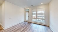 Located at 1101 Lady St in downtown Columbia, SC, this well-appointed 2-bedroom, 2-bathroom unit is spread across a single floor and offers a thoughtfully designed, modern interior. Light-toned wood-look flooring runs throughout the living areas and bedrooms, providing a cohesive and contemporary aesthetic.

The open-concept kitchen and living area serves as the heart of the unit. The kitchen features two-tone cabinetry—white upper cabinets paired with sage-green lower cabinets—complemented by a white tile backsplash, light countertops, and stainless steel appliances including a range, microwave, and refrigerator. A large island with pendant lighting above anchors the space, offering both functionality and a natural gathering point.

The living area benefits from oversized windows and a glass-paneled door that frame views of the surrounding downtown streetscape, allowing natural light to fill the room.

Both bedrooms are comfortably sized with ample wall space and large windows. One bedroom features double closet doors with black hardware. The bathrooms are finished with large-format marble-style tile flooring, white vanities with black hardware, and lighted mirrors. One bathroom includes accessibility-focused grab bars and a soaking tub with tile surround.