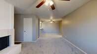 This single-story, 3-bedroom, 2-bathroom home offers a thoughtfully arranged floor plan designed for comfortable everyday living. The spacious living room serves as the heart of the home, featuring plush carpet flooring, neutral gray walls, ceiling fans with integrated lighting, and a charming brick fireplace — an inviting focal point that adds character to the space. A textured ceiling is consistent throughout, lending a classic residential feel.

The kitchen is well-equipped with light gray cabinetry, white quartz-style countertops, a subway tile backsplash, and black appliances including a range, refrigerator, and dishwasher. Rich hardwood-style flooring anchors the kitchen and flows through the adjacent areas, creating a clear distinction between living and utility spaces.

Each of the three bedrooms is carpeted and features ceiling fans, neutral walls, and ample natural light from windows dressed with blinds or vertical slat coverings. The primary bedroom includes access to a dedicated closet. The bathrooms are clean and functional, with one featuring a tub/shower combo, wood-style flooring, and a vanity with a speckled countertop. Three closets distributed throughout the home provide generous storage. A connecting hallway ties all rooms together in a cohesive, easy-to-navigate layout.