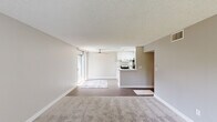 This single-floor residence offers a practical and comfortable layout across three bedrooms and two bathrooms. The open-concept living room is a welcoming central space, featuring neutral-toned carpet, a ceiling fan, and a large sliding glass door that fills the room with natural light. The galley-style kitchen is bright and functional, highlighted by a skylight overhead, white cabinetry with brushed nickel hardware, white countertops, a stainless steel sink, and a full suite of appliances including a range and refrigerator. Light wood-style flooring runs throughout the kitchen, adding warmth to the clean aesthetic.

The three bedrooms are finished with plush carpeting and neutral walls, creating a calm and restful atmosphere. The spacious primary bedroom benefits from a large window with views of surrounding greenery, and connects to a well-appointed bathroom featuring a dual-sink vanity with white countertops, framed mirrors, and stylish overhead lighting. The second bathroom is cleanly finished with wood-style flooring and bright white walls. Hallways connect the rooms efficiently throughout the unit, and a dedicated closet provides additional storage. Textured ceilings are consistent throughout, adding a characteristic finish to the overall design.