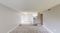This single-floor residence offers a practical and comfortable layout across three bedrooms and two bathrooms. The open-concept living room is a welcoming central space, featuring neutral-toned carpet, a ceiling fan, and a large sliding glass door that fills the room with natural light. The galley-style kitchen is bright and functional, highlighted by a skylight overhead, white cabinetry with brushed nickel hardware, white countertops, a stainless steel sink, and a full suite of appliances including a range and refrigerator. Light wood-style flooring runs throughout the kitchen, adding warmth to the clean aesthetic.

The three bedrooms are finished with plush carpeting and neutral walls, creating a calm and restful atmosphere. The spacious primary bedroom benefits from a large window with views of surrounding greenery, and connects to a well-appointed bathroom featuring a dual-sink vanity with white countertops, framed mirrors, and stylish overhead lighting. The second bathroom is cleanly finished with wood-style flooring and bright white walls. Hallways connect the rooms efficiently throughout the unit, and a dedicated closet provides additional storage. Textured ceilings are consistent throughout, adding a characteristic finish to the overall design.
