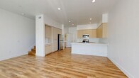 Located in Lancaster, CA, this well-appointed two-story home offers 2 bedrooms and 3 bathrooms across two thoughtfully designed floors. The main level features an open-concept kitchen and living area bathed in natural light from large sliding glass doors with vertical blinds. The kitchen is a standout, showcasing light wood flat-panel cabinetry, crisp white quartz countertops, a central island with an undermount sink, and a full suite of stainless steel appliances. Warm wood-look luxury vinyl plank flooring runs throughout, tying the spaces together cohesively. The living area offers generous proportions and direct outdoor access, creating a bright and airy atmosphere. Upstairs, the primary bedroom is a spacious retreat featuring large windows with outdoor views and a well-organized walk-in closet with built-in shelving and dual hanging rods. The additional bedroom is equally bright, with wide windows that invite natural light. All three bathrooms are finished in a clean, modern aesthetic with tub-shower combos featuring brushed nickel fixtures, white subway tile surrounds, and light wood vanities with white countertops. Clean white walls, recessed lighting, and consistent flooring throughout give the entire home a fresh, contemporary feel.
