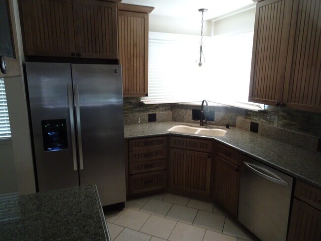 Cocina esquinera con ventana, electrodomésticos de acero inoxidable y encimeras de granito. - 5643 Cedros Ave