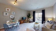Located at 1455 Washington Blvd in Stamford, Connecticut, this single-floor residence offers a thoughtfully designed layout that balances comfort and functionality. The open-concept living and dining area is anchored by plush carpeting, neutral-toned walls, and a sliding glass door that leads to a private balcony, filling the space with natural light and providing outdoor views. Track lighting and stylish fixtures add a contemporary touch to the living area's welcoming ambiance.

The kitchen features a peninsula with a dark granite-style countertop that provides bar seating and separates the cooking space from the living area. White cabinetry and stainless steel appliances contribute to a clean, modern aesthetic, while hardwood-style flooring grounds the space.

The bedroom is generously proportioned, featuring soft carpeting, large windows dressed with elegant curtains, and ample room for a full furniture arrangement including a dresser, desk, and seating area. The calm, neutral palette creates a restful retreat.

The bathroom is clean and well-lit, with tile flooring, a white vanity with storage, a large mirror, and a bright vanity light fixture. The overall design of this residence prioritizes comfort, practicality, and a light, airy atmosphere throughout.