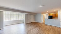 Located at 11731 S Laurel Dr in Laurel, Maryland, this single-floor, 3-bedroom, 2-bathroom home offers a well-organized and functional layout. The open living area is a standout feature, showcasing light-toned wood-look flooring that runs throughout the main spaces, soft neutral gray walls, and a wide bank of windows dressed with vertical blinds that fill the room with natural light. Recessed lighting and track lighting add to the bright, airy atmosphere. The living area flows into a dedicated kitchen space equipped with warm wood cabinetry, granite-look countertops, black appliances including a refrigerator, range, and over-the-range microwave, and continued wood-look flooring. The three bedrooms are finished with plush wall-to-wall carpeting, and the spacious primary bedroom includes a ceiling fan, a window with outdoor views, and a sliding-door closet. Additional bedrooms feature arched-panel doors and access to closet space, with four closets distributed throughout the home. The bathrooms are cleanly finished, with one featuring a glass-door shower stall and chrome fixtures. The layout is efficient and cohesive, with a consistent neutral color palette and clean finishes creating a comfortable, move-in ready environment throughout.