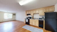 This one-bedroom, one-bathroom residence in Haverhill, MA offers a practical and well-organized layout across a single floor. The open living and kitchen area features warm-toned hardwood flooring that runs throughout, creating a cohesive and inviting atmosphere. The kitchen is equipped with light maple cabinetry offering ample storage, granite-style countertops, and a full suite of black appliances including a refrigerator, electric range, dishwasher, and built-in microwave hood. A textured ceiling adds visual character to the space.

The bedroom is a comfortable, well-proportioned retreat finished with plush gray carpeting underfoot and a large closet with sliding panel doors. A window allows natural light to filter in, providing views of the surrounding neighborhood. Baseboard heating ensures warmth throughout the cooler months.

The bathroom is finished with classic white subway tile surrounding the tub-shower combination, complemented by neutral walls and easy-to-maintain flooring. The space is clean and functional, with room for essential storage. Overall, this unit delivers a straightforward, livable design suited for those seeking a cozy and efficient home in the Haverhill area.