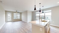 This well-designed 2-bedroom, 1-bathroom residence at 550 Stanton St in Frederick, MD offers a thoughtfully planned open-concept layout with modern finishes throughout. The combined kitchen and living area serves as the heart of the home, featuring light wood-tone flooring, large windows that invite generous natural light, and a ceiling fan that enhances the airy atmosphere. A door leads directly to a private balcony, extending the living space outdoors with neighborhood views.

The kitchen is a standout feature, showcasing a large center island with a white quartz countertop and an integrated sink with a brushed gold faucet. Sleek white cabinetry with glass-front uppers, a gray subway tile backsplash, stainless steel appliances, and striking black pendant lights complete the contemporary look.

Both bedrooms are carpeted for comfort and finished with neutral tones, offering a calm and restful environment. The spacious primary bedroom provides ample room to furnish comfortably. The bathroom is finished with a white vanity, clean countertops, and wood-look flooring. A dedicated closet with built-in shelving adds practical storage. The consistent use of neutral tones and clean lines throughout gives this residence a cohesive, modern character.
