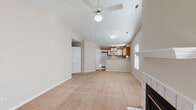 Located at 2707 Meridian Dr in Greenville, NC, this single-floor residence offers a well-designed, open layout that maximizes comfort and functionality. The living area is a standout space, featuring soaring vaulted ceilings, a ceiling fan, and a tile-surround fireplace that serves as a natural focal point. Plush carpeting runs throughout the main living and bedroom areas, lending a warm, comfortable feel. The kitchen is efficiently arranged with a peninsula breakfast bar that opens to the living space, warm wood-toned cabinetry with white panel accents, and white appliances including a range, built-in microwave, refrigerator, and dishwasher. Tile flooring anchors the kitchen and bathrooms. The primary bedroom impresses with its own vaulted ceiling, a large arched window that floods the room with natural light, a ceiling fan, and a spacious walk-in closet. Additional bedrooms are generously sized, each with ceiling fans and closet space. A secondary bedroom provides access to an outdoor patio through glass doors. The bathrooms are appointed with wood-toned vanities, wide mirrors, and tile flooring, with the primary bath featuring an extended vanity and separate soaking tub. A large walk-in closet and a dedicated laundry area with washer/dryer connections round out the practical storage offerings throughout this well-appointed home.